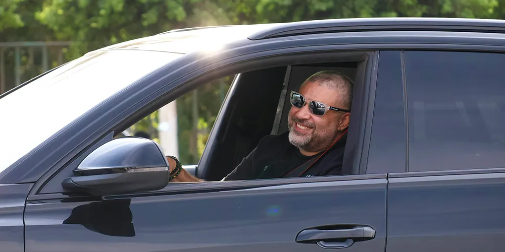 A man driving home happy with a new used car